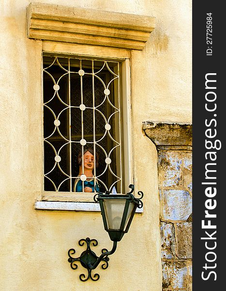 Old-school windows with a lamp and a sculpture of a child in the windows