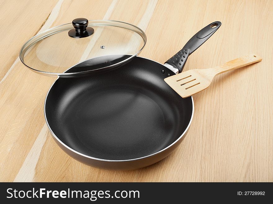 Frying pan with lid on wooden table. Frying pan with lid on wooden table