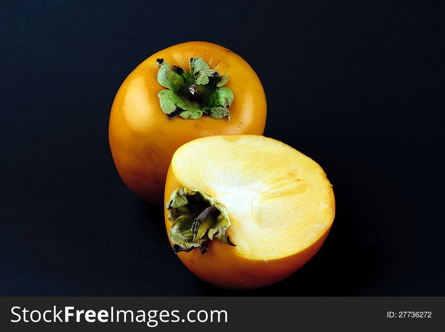 Portrait photo of a full and a half piece of sharon fruit. Portrait photo of a full and a half piece of sharon fruit