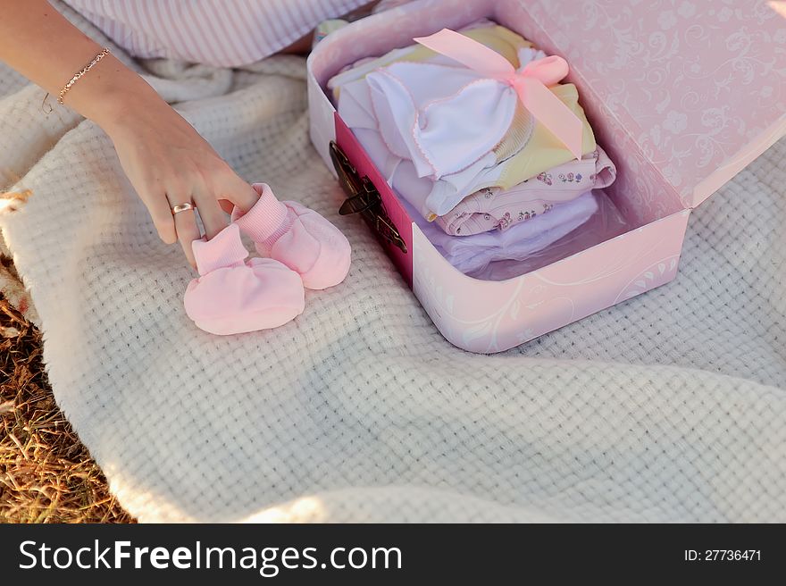 Pretty pregnant woman with childrens clothes at home. Pretty pregnant woman with childrens clothes at home