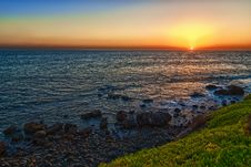 Sunset On A Calm Sea With A Green Grass And Rocks Royalty Free Stock Photo