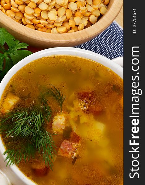 Pea Soup with Potato and Smoked Ham in Bowl closeup on Yelow Peas Bowl background