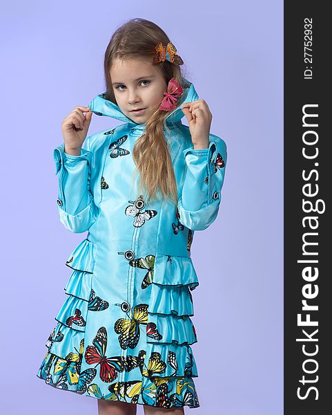 Portrait of a cute little girl in a beautiful colored coat with butterflies posing in studio. Portrait of a cute little girl in a beautiful colored coat with butterflies posing in studio