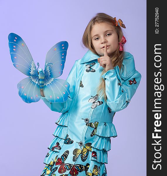 Portrait of a cute little girl in a beautiful colored coat with butterflies posing in studio. Portrait of a cute little girl in a beautiful colored coat with butterflies posing in studio