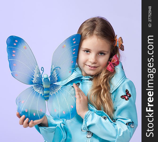 Portrait of a cute little girl in a beautiful colored coat with butterflies posing in studio. Portrait of a cute little girl in a beautiful colored coat with butterflies posing in studio