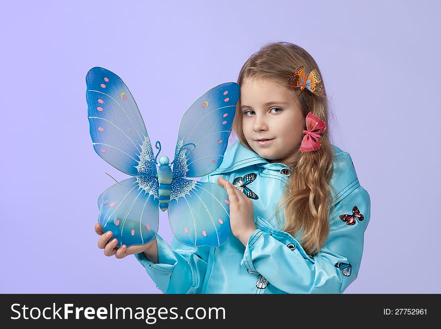 Portrait of a cute little girl in a beautiful colored coat with butterflies posing in studio. Portrait of a cute little girl in a beautiful colored coat with butterflies posing in studio