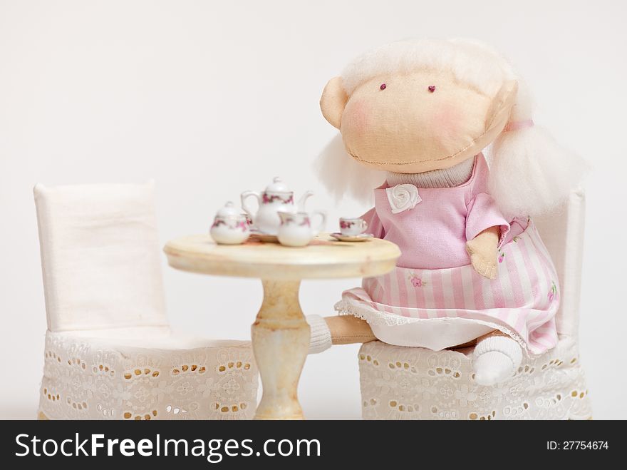 Handmade toy cute litlle girl having a tea. Handmade toy cute litlle girl having a tea