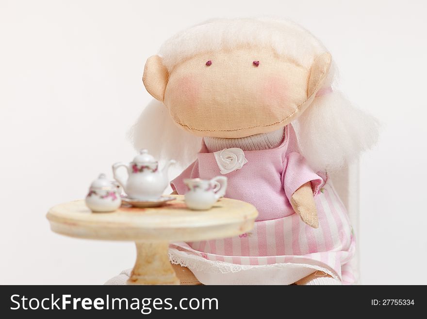 Handmade toy cute litlle girl having a tea. Handmade toy cute litlle girl having a tea