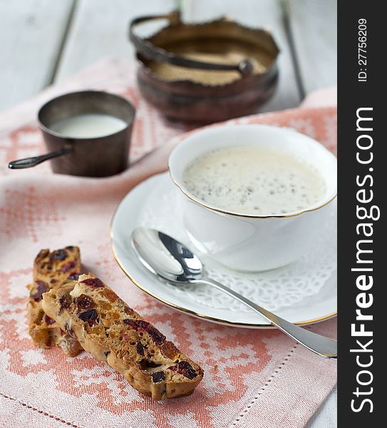 A cup of coffee and biscotti on a wooden table. A cup of coffee and biscotti on a wooden table
