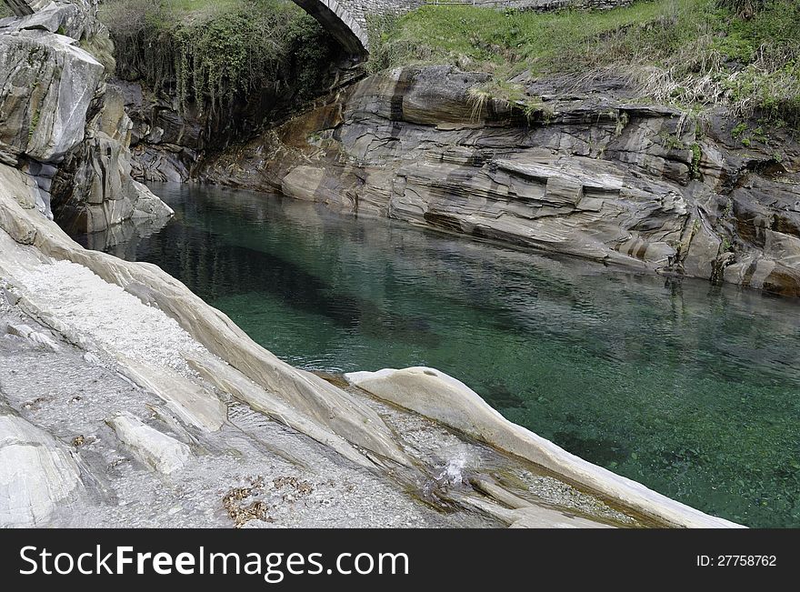 View of the Verzasca River near an old bridge in the Verzasca Valley in the Ticino area of Switzerland. Verzasca means green water and this is really true for that fascinating stream. The rocks are as colourful as the river in their many shades. View of the Verzasca River near an old bridge in the Verzasca Valley in the Ticino area of Switzerland. Verzasca means green water and this is really true for that fascinating stream. The rocks are as colourful as the river in their many shades.