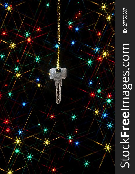 Key on a gold chain on a background of colored lights of the Christmas tree. Key on a gold chain on a background of colored lights of the Christmas tree