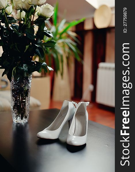 On the wooden floor are white shoes for the bride with dressing. On the wooden floor are white shoes for the bride with dressing