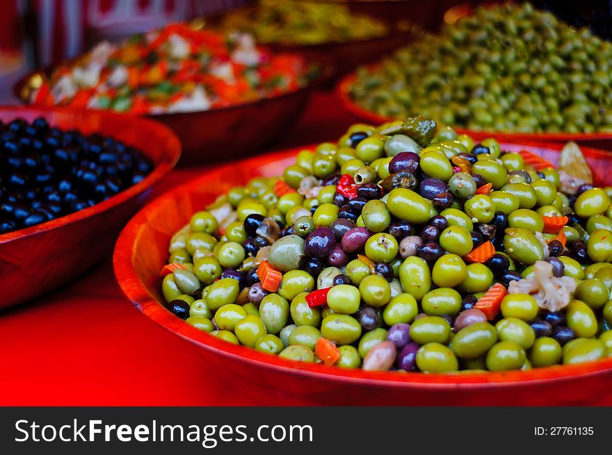 Green and black olives compasition in a red bowl at the market of Milly la Foret, France