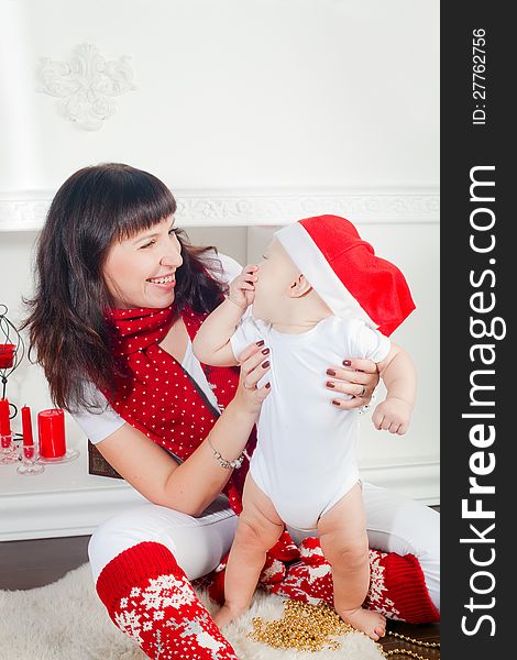 Young mother holding her little son, it is Christmas time, the boy wearing Santa's hat, they are laughing. Young mother holding her little son, it is Christmas time, the boy wearing Santa's hat, they are laughing