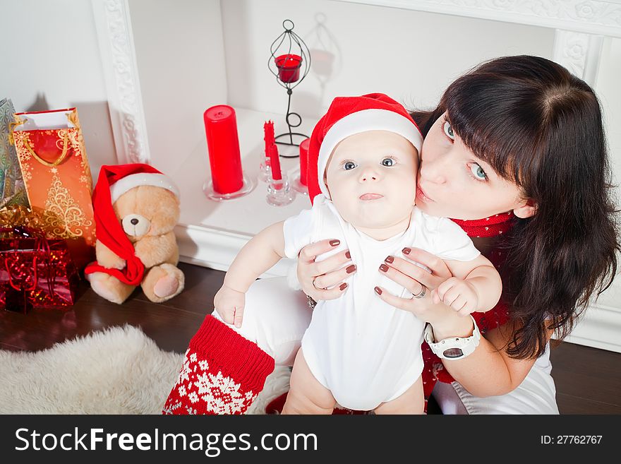 Young mother kissing her little son, the boy is in Santa's cap. Young mother kissing her little son, the boy is in Santa's cap