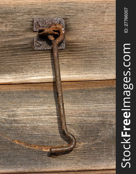 Antique rusty barn door latch fixed to weathered wooden boards