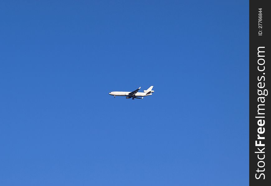 White airplane in the blue sky, coming in for landing