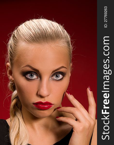Sexy girl with aggressive makeup on a dark red background
