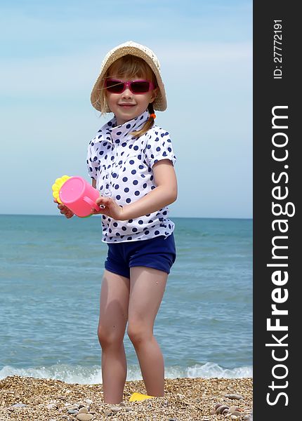 The smiling girl in sunglasses with a toy on the background of the sea. The smiling girl in sunglasses with a toy on the background of the sea