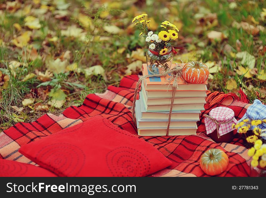 Outdoors ripe pumpkin and a stack of books with a bouquet of autumn flowers. Outdoors ripe pumpkin and a stack of books with a bouquet of autumn flowers