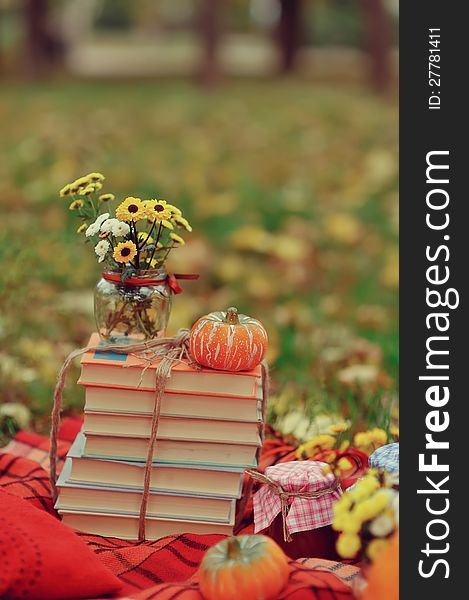 Outdoors ripe pumpkin and a stack of books with a bouquet of autumn flowers. Outdoors ripe pumpkin and a stack of books with a bouquet of autumn flowers