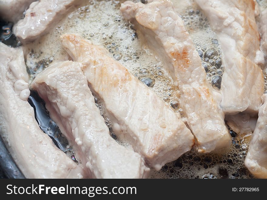 A closeup of pieces of meat being fried in oil. A closeup of pieces of meat being fried in oil