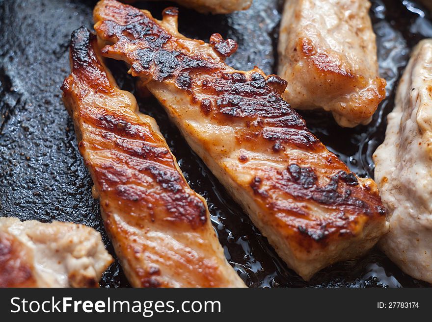 A closeup of pieces of meat being fried in oil. A closeup of pieces of meat being fried in oil