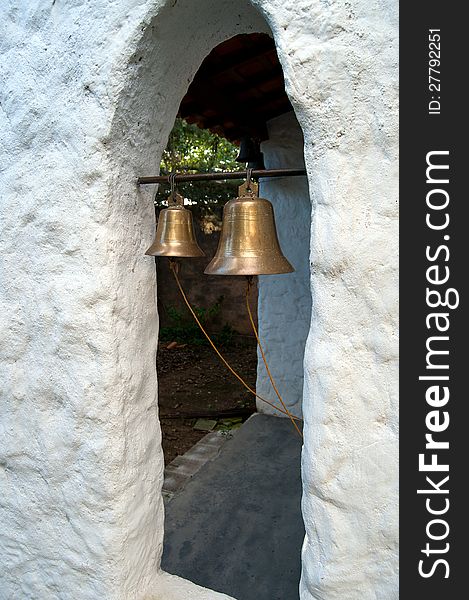 Two Brass bells hanging in old church window. Two Brass bells hanging in old church window