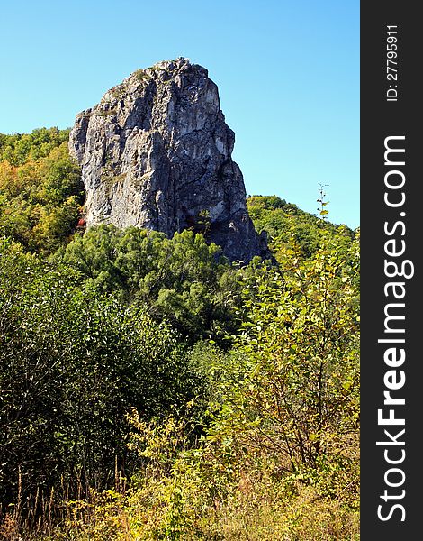 High rock among wood. Rock in a taiga. Russia