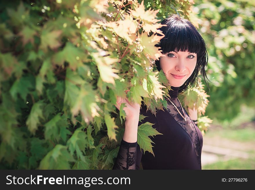 Young woman standing near a maple with lush foliage