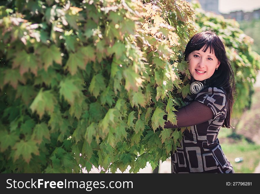 Young woman standing near a maple with lush foliage