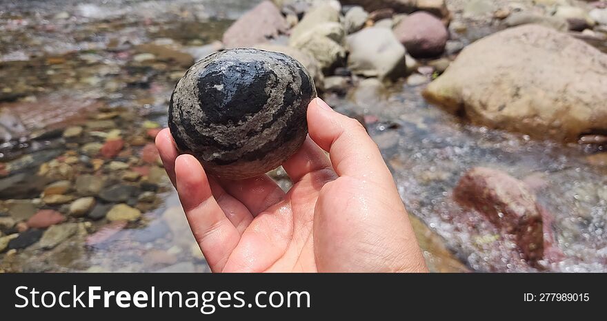 A hand holds a beautiful river rock