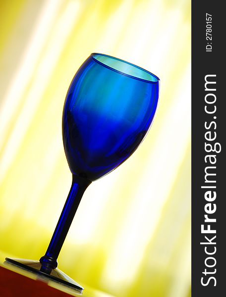 Blue cobalt wine glass on yellow background