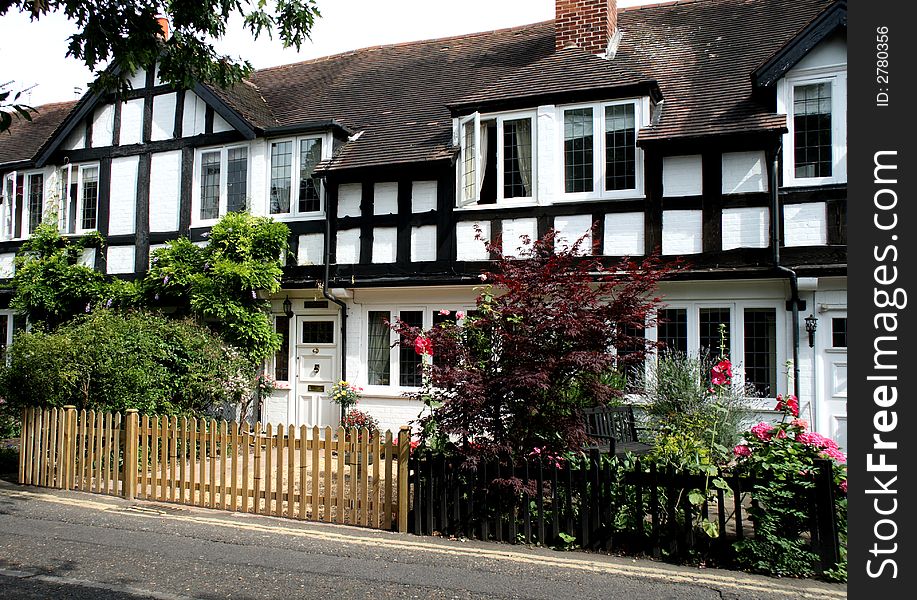 Row of Timber Framed English Village Cottages with a picket fence in front. Row of Timber Framed English Village Cottages with a picket fence in front.