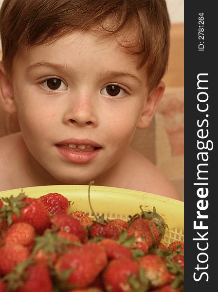 The child looks at a plate with red berries