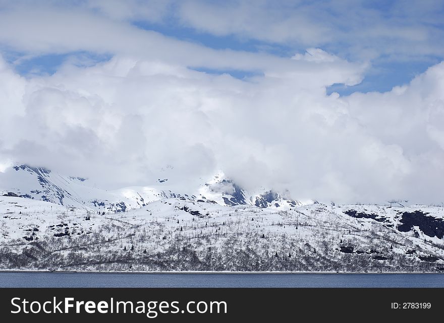 The range of mountains and clouds over it in Glacier Bay national park, Alaska. The range of mountains and clouds over it in Glacier Bay national park, Alaska.