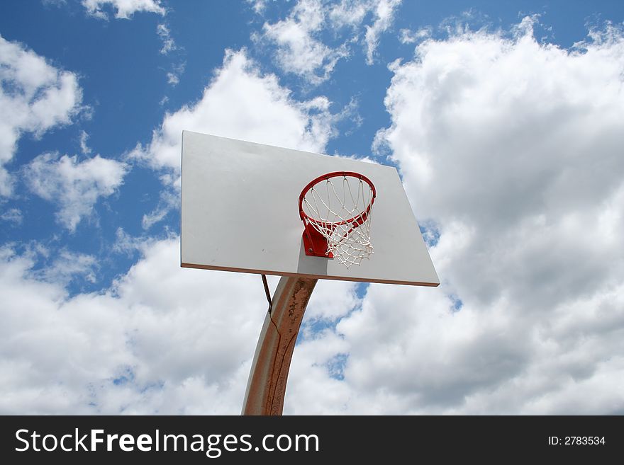 An image of a Basketball hoop against a cloudy sky. An image of a Basketball hoop against a cloudy sky