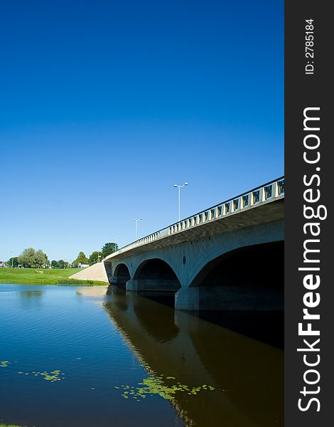 Bridge. Reflection in river. Blue sky.