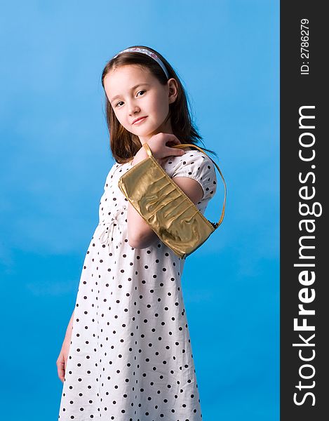 The girl of ten years poses with a gold handbag in a hand. The girl of ten years poses with a gold handbag in a hand