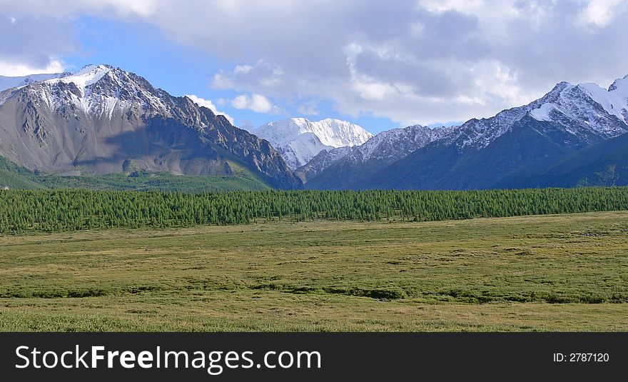 There is fine mountain valley framed by mountains which are covered with a snow. There is fine mountain valley framed by mountains which are covered with a snow.