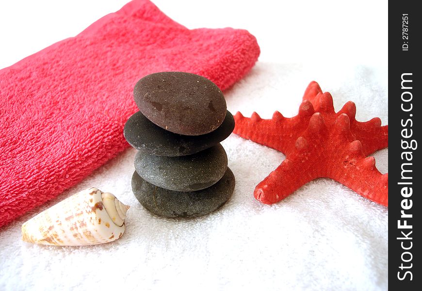 Spa essentials (pyramid of stones with white towel and seashell)