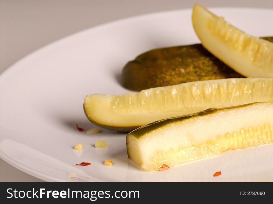 Kosher dill pickle spears on a white plate with a gray background