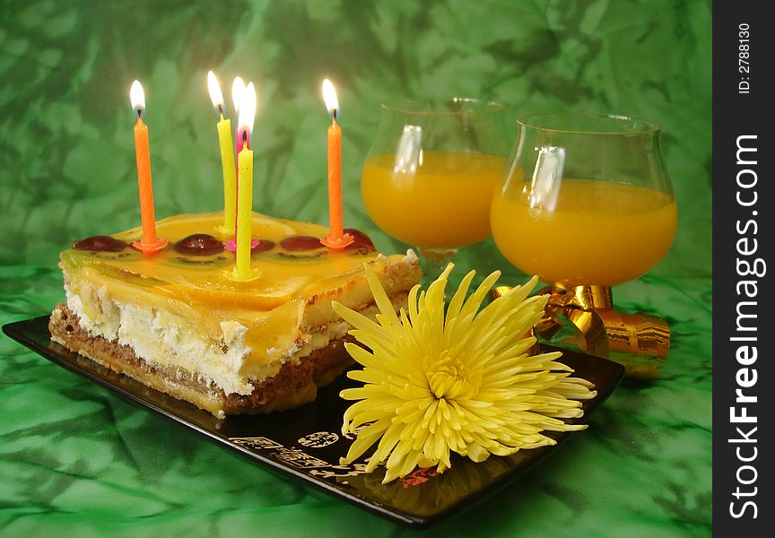 Celebratory table (cake and candles, two glasses) on green