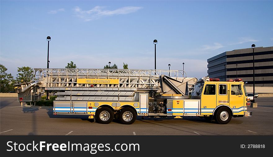 This is a side view of a fire truck with ladders and a bucket used for reaching fires in high places. This is a side view of a fire truck with ladders and a bucket used for reaching fires in high places.