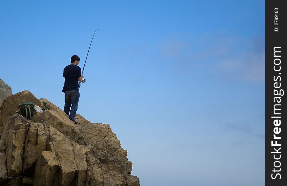 Young adult fishing on the top of a cliff. Young adult fishing on the top of a cliff