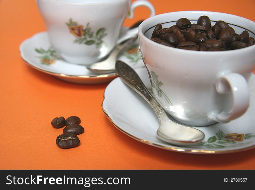 Grains of coffee and cup on an orange background