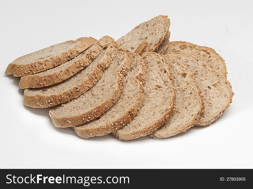 Loaf of rye bread cut on pieces on a white background