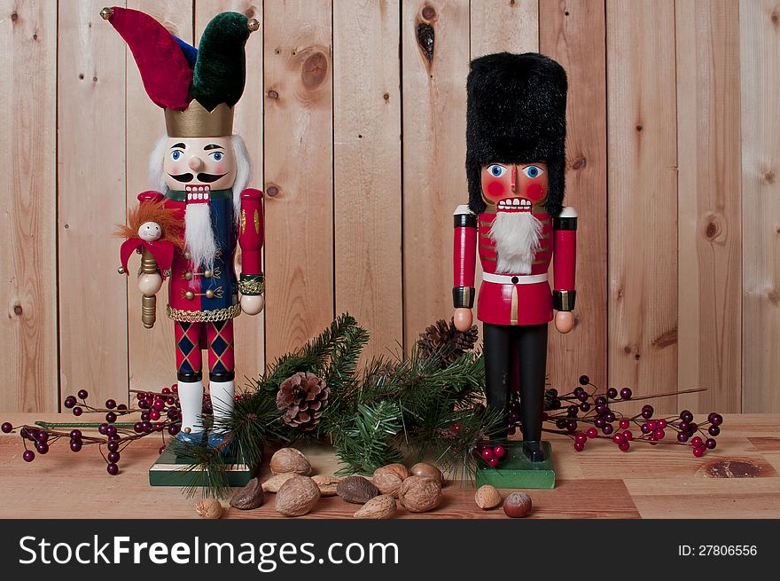 Two wooden nutcrackers with assorted nuts and garland on wood background. Two wooden nutcrackers with assorted nuts and garland on wood background