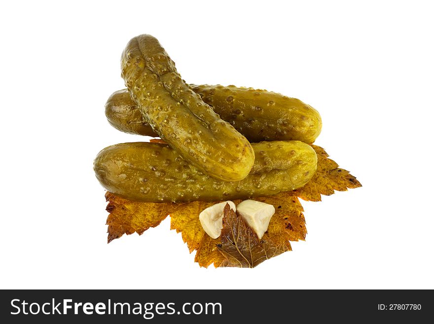 Pickled cucumbers on currant sheet with slices of garlic isolated on white background