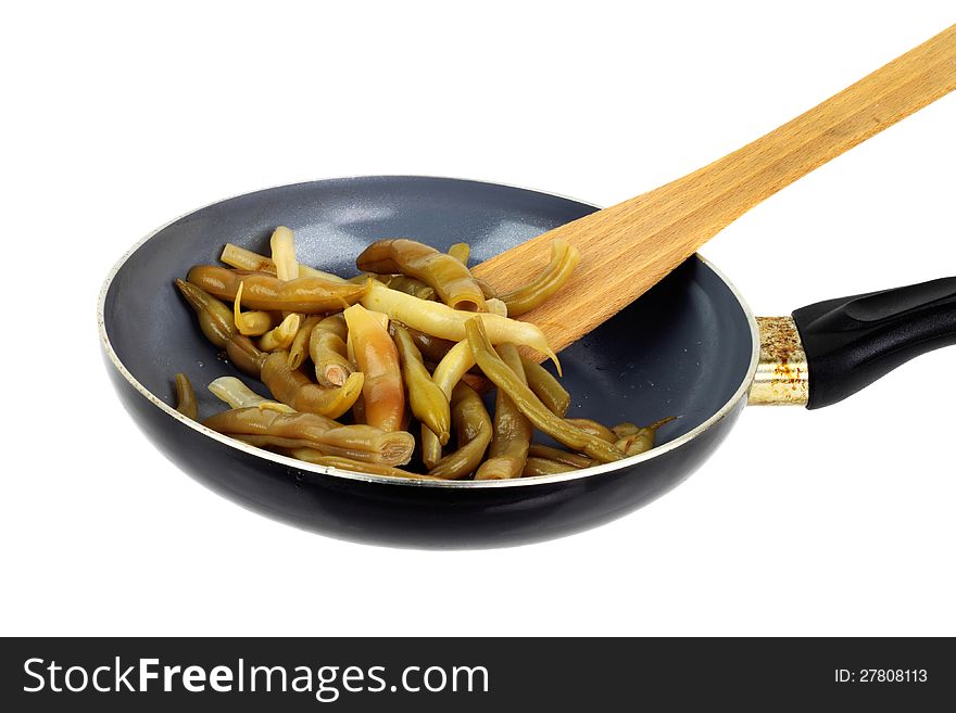 Stewed French bean on the pan with wooden scapula isolated on white background. Stewed French bean on the pan with wooden scapula isolated on white background